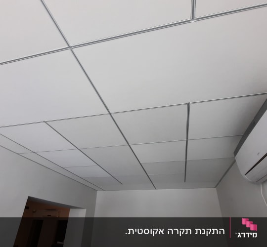 תקרה אקוסטית פריקה עם אריחים ריבועיים ומזגן מותקן על הקיר